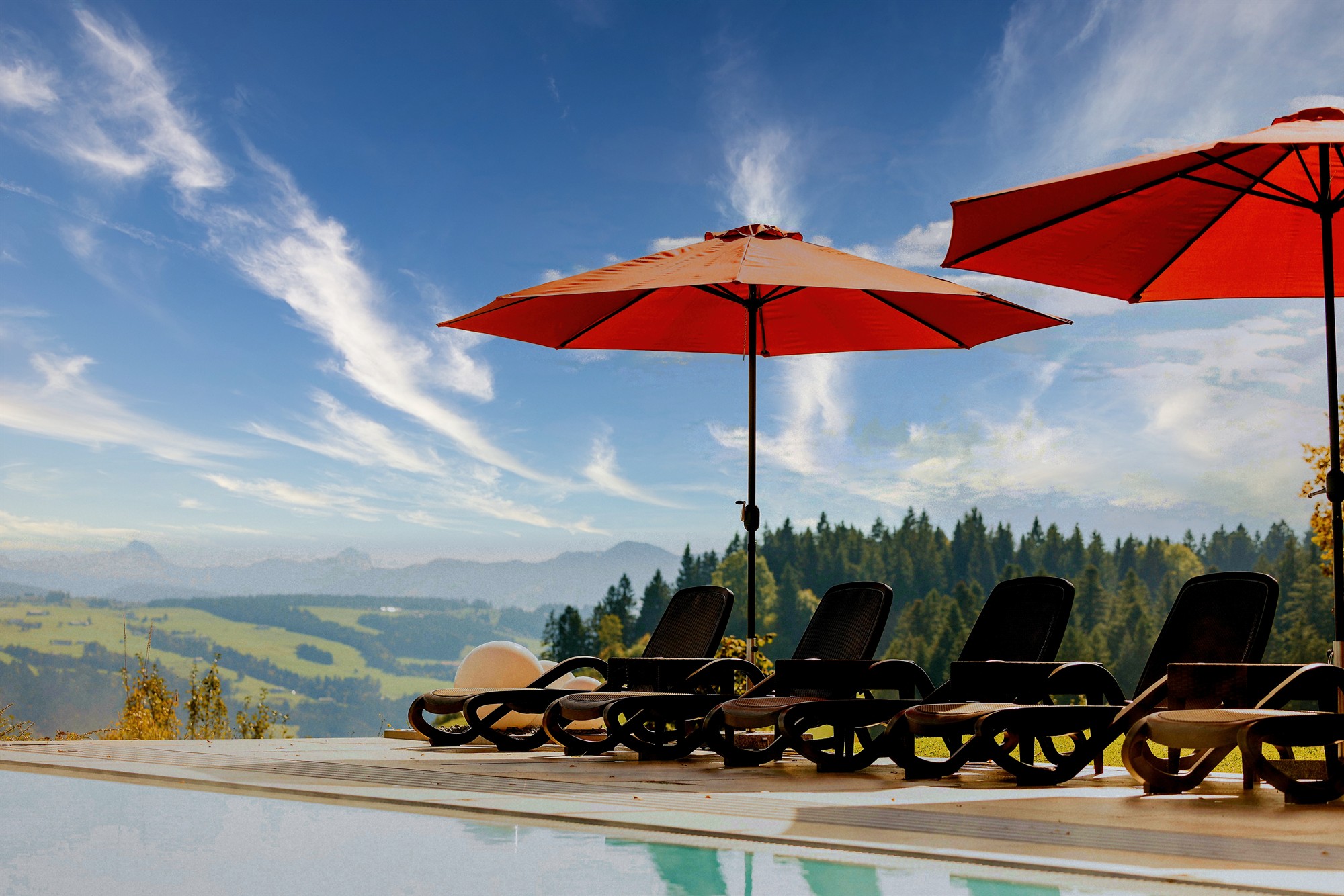 Außenpool mit Sonnenliegen und Bergblick